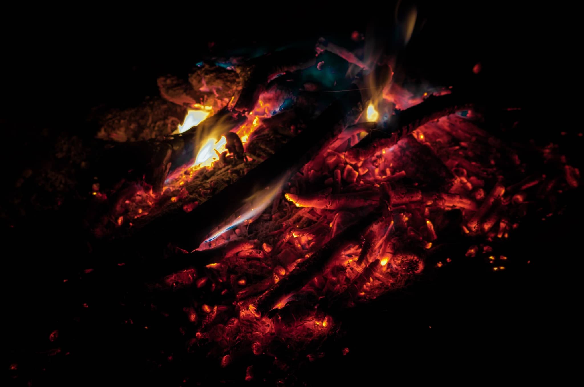 A campfire, with the fire slowly becoming smaller which eventually will extinguish. Photo by Justin Chavanelle on Unsplash.